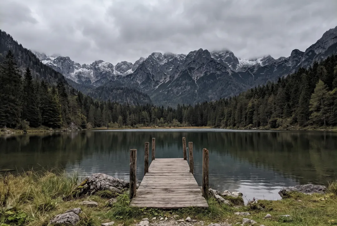 Alpine lake and wooden pier under an overcast sky