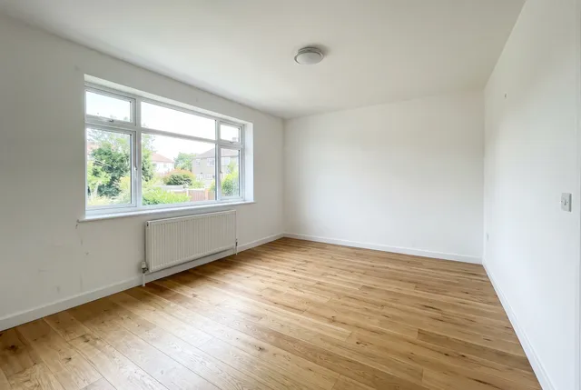 Empty living room with white walls and an oak floor