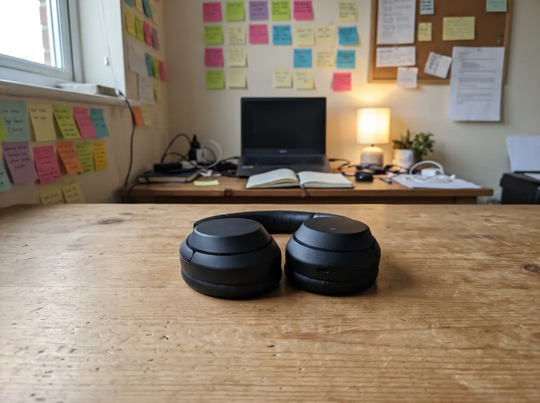 Black over-ear headphones on a wooden desk, original photo
