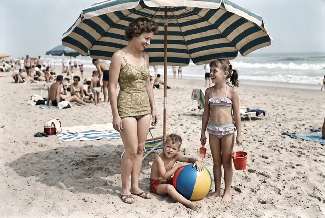 Colorized photo of a 1950s mother and two children on a beach