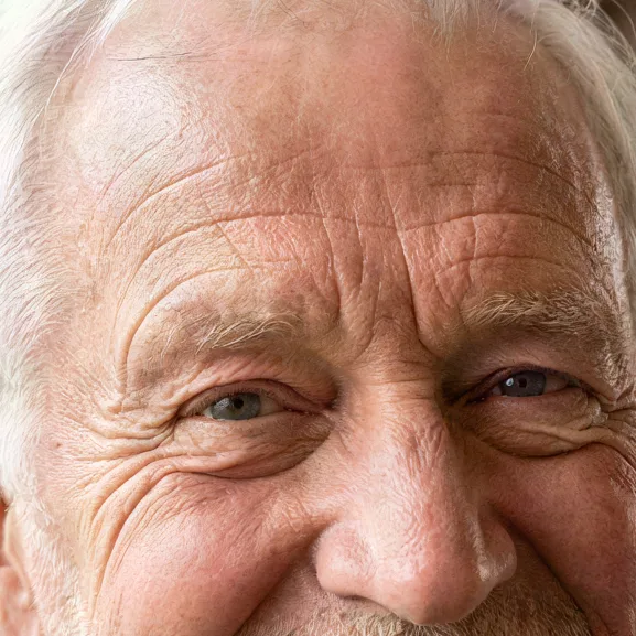 Smiling grandfather in a wool cardigan by a window, upscaled 4× with AI, 100% crop