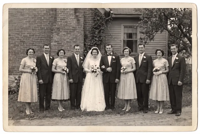 Restored photo of a 1950s wedding party of ten in front of a brick house