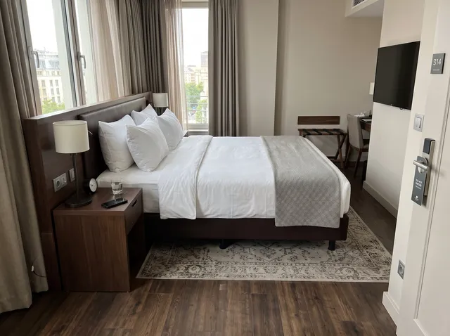 Hotel-style bedroom with a white bed, after removing the open suitcase and charger cable