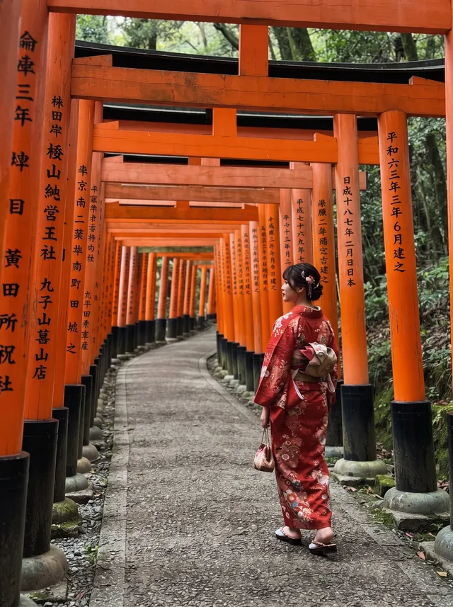 Woman in a red kimono walking through torii gates, after removing the man in gray hoodie