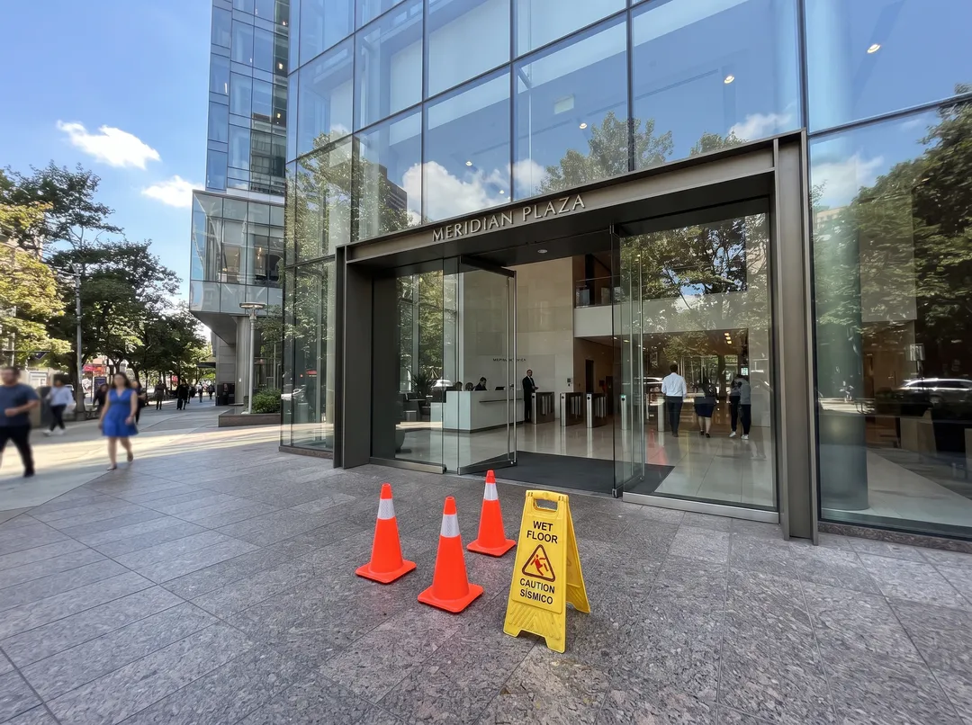 Glass office building entrance, with traffic cones and sign in the shot