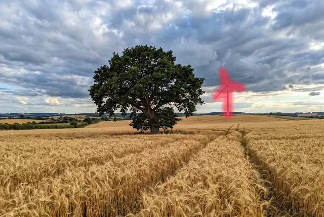 Wheat field with a lone oak tree, wind turbine painted over with the red brush